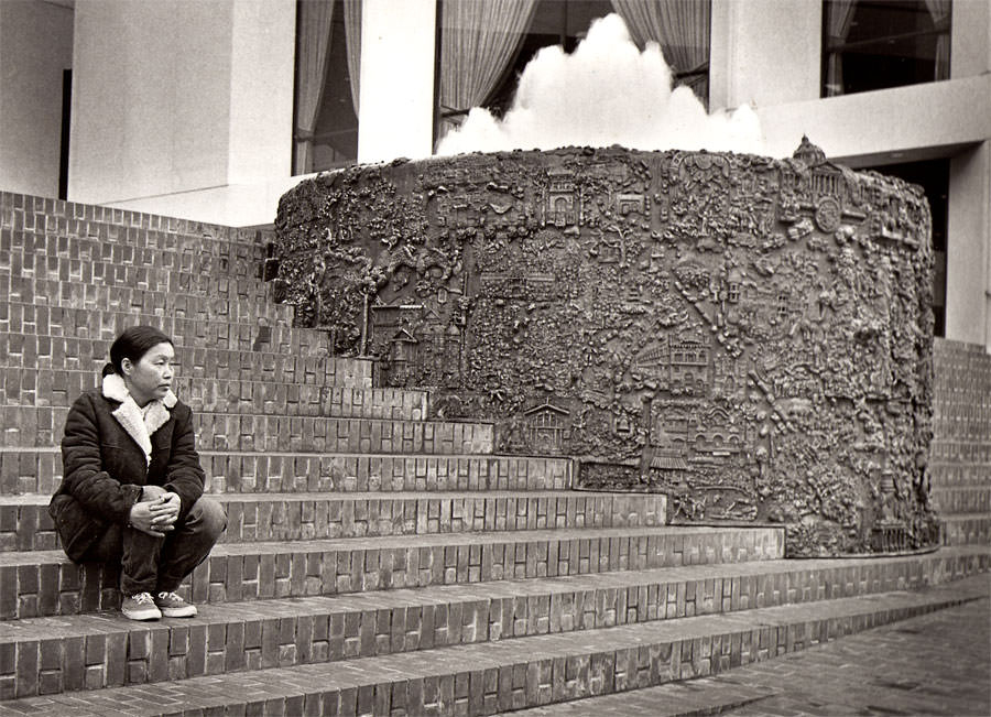 Asawa seated next to her bas-relief bronze sculpture at the Grand Hyatt hotel in San Francisco